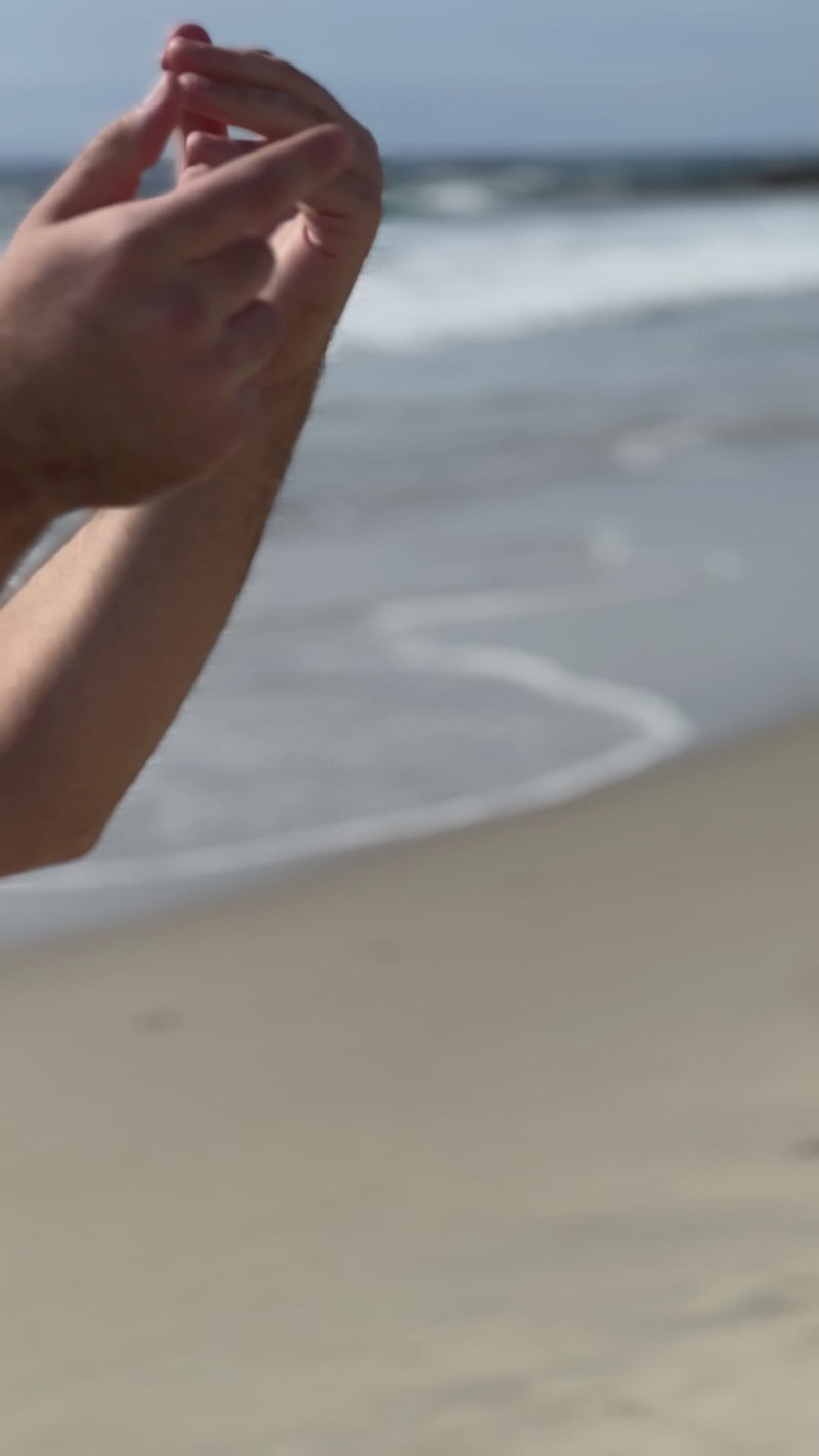 Mako Vitality Mango sea moss gel in a glass jar on a sandy beach held in hand
