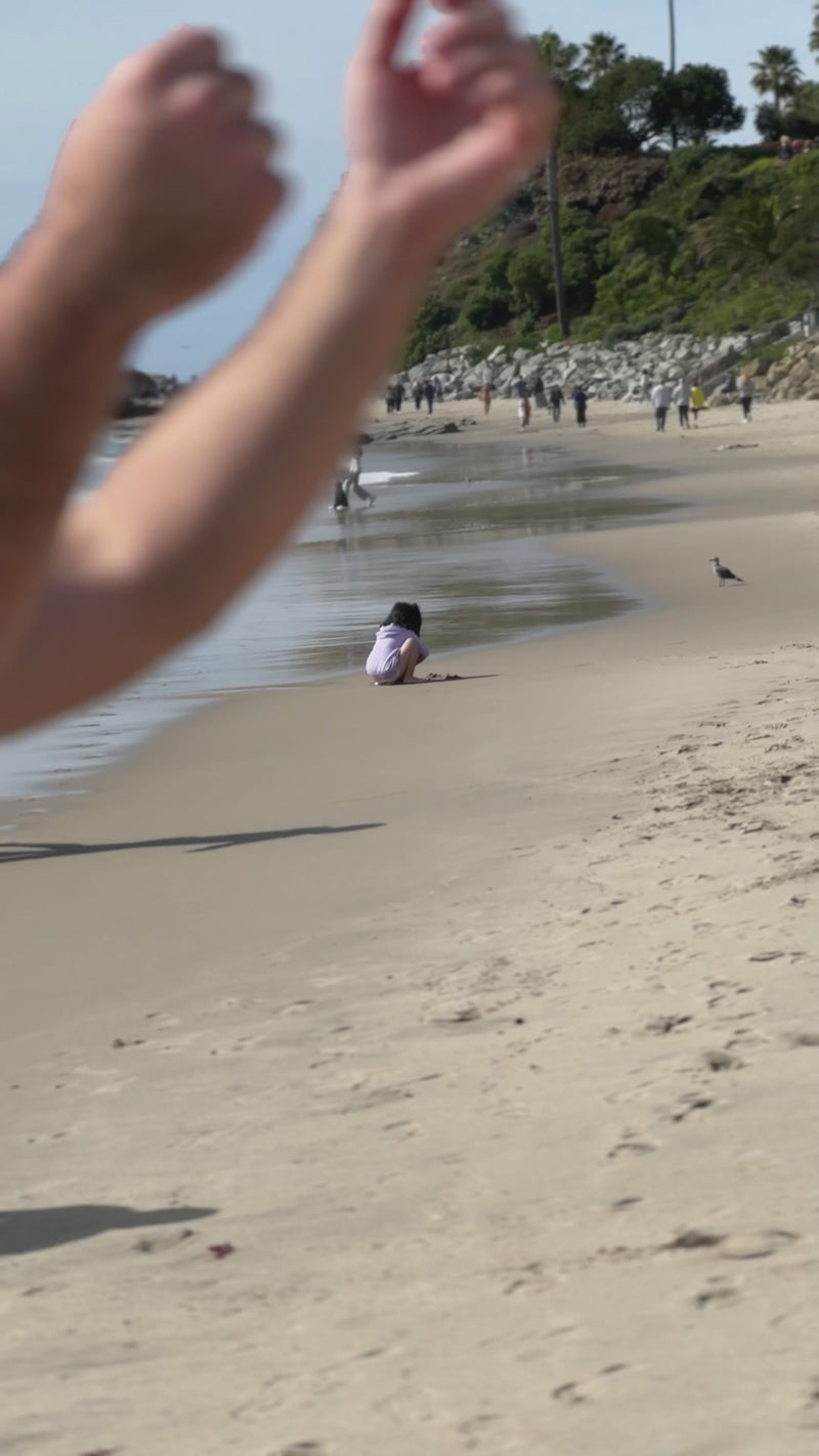 Mako Vitality Strawberry sea moss gel in a glass jar on a sandy beach held in hand